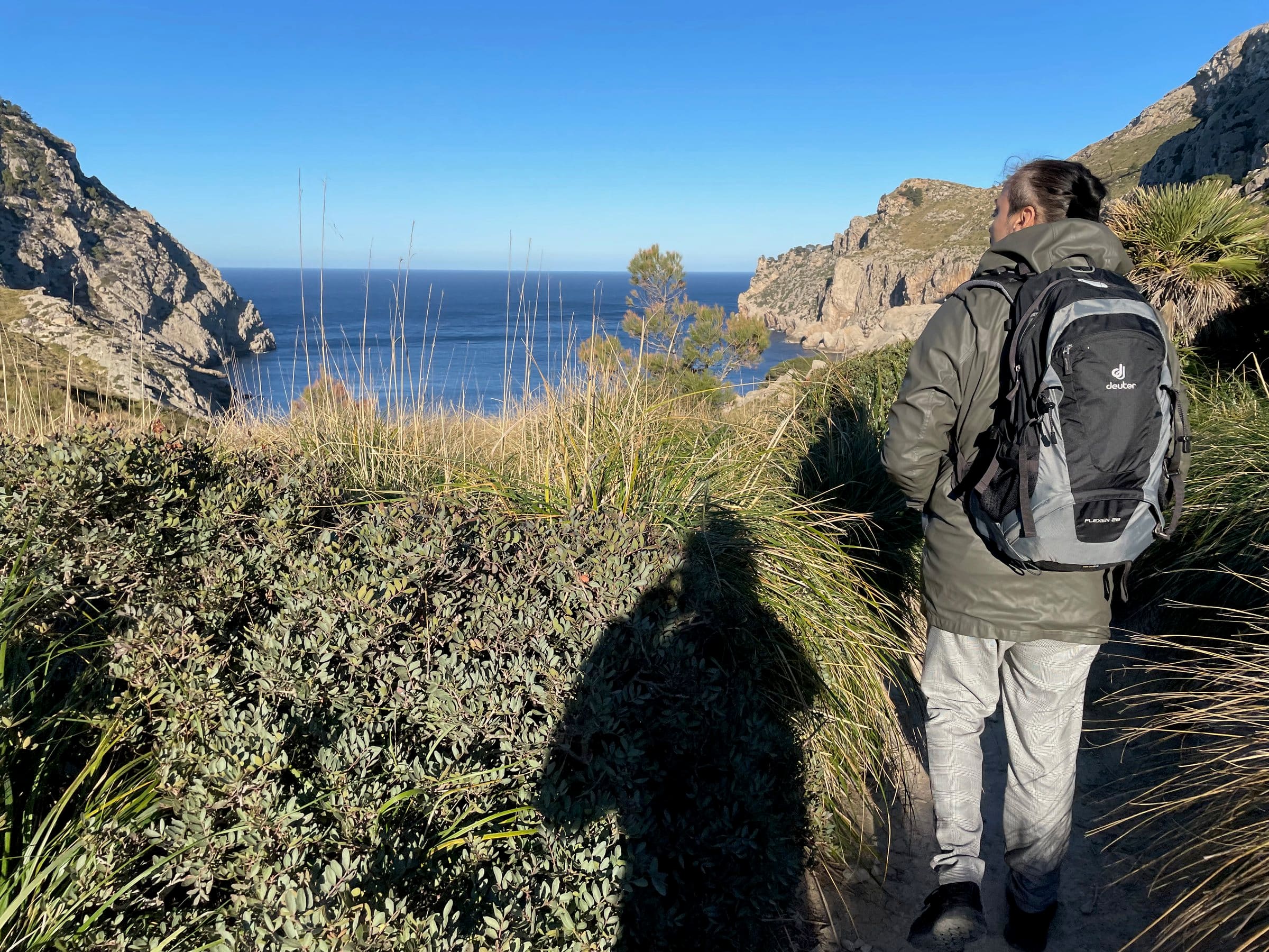 Dave mit Rucksack von hinten auf einem Küstenpfad, vor ihm das Meer